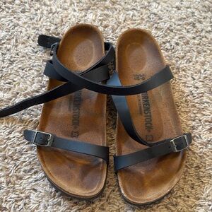 Black Birkenstocks with strap that goes around the ankle.